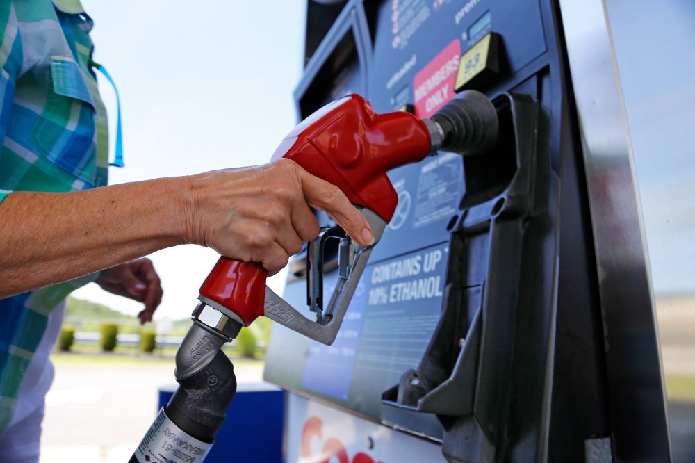 Image: A woman holds a nozzle as she refuels her car