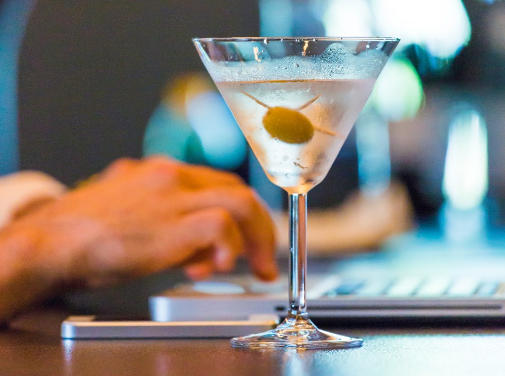 Image: A man on a laptop with a martini