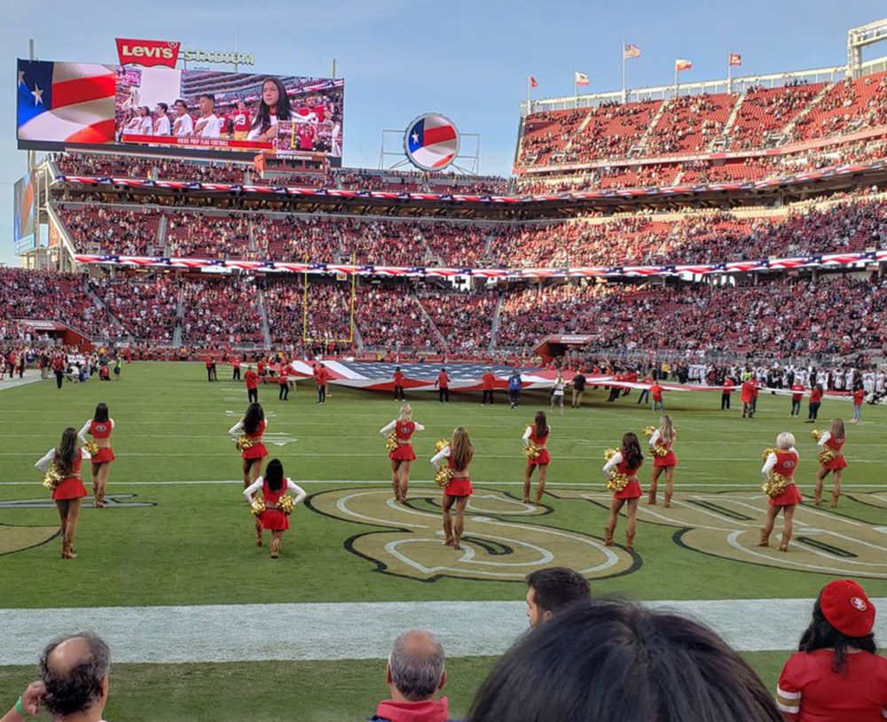 Image: A San Francisco 49ers cheerleader kneels during the national anthem