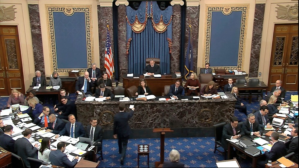 Image: A Senate page brings the first question to presiding officer Chief Justice of the United States John Roberts from the majority to read during the impeachment trial against President Donald Trump in the Senate at the U.S. Capitol