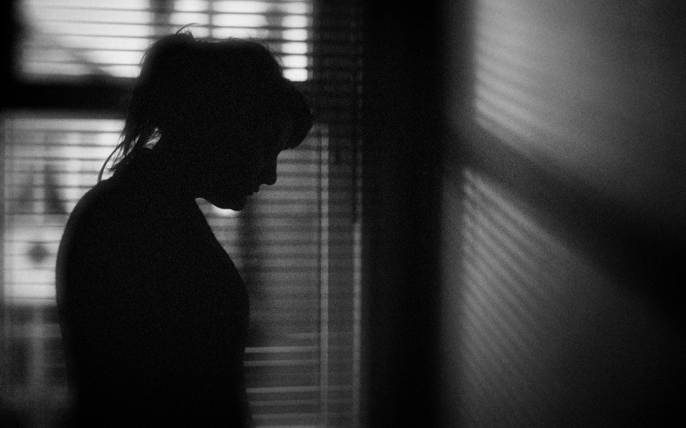 Image: The silhouette of a woman standing by a window.