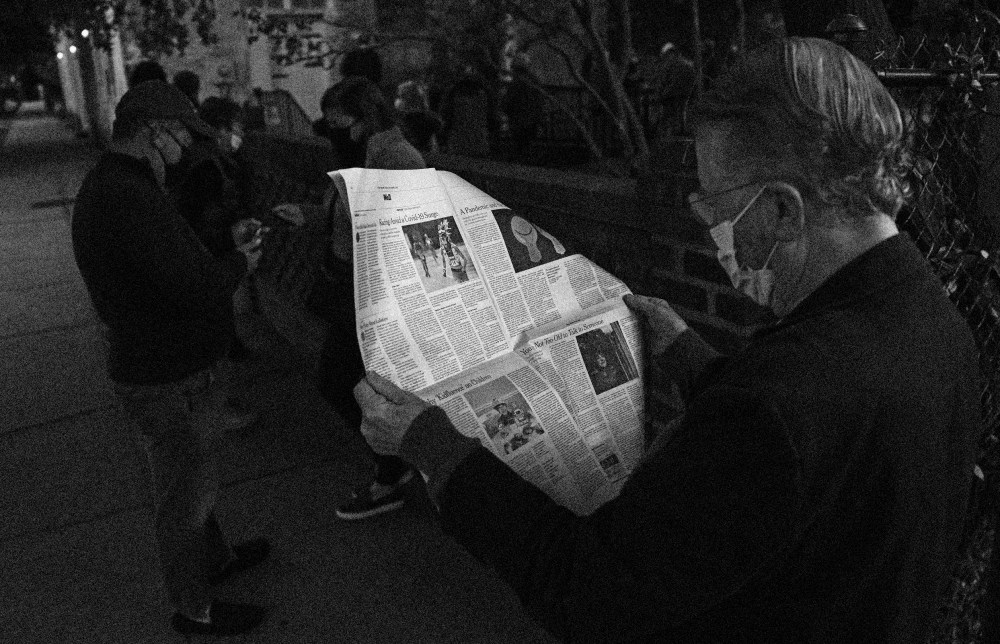 Image: John Winthrop reads a newspaper as he waits to vote in Charleston, S.C., on Nov. 3, 2020.