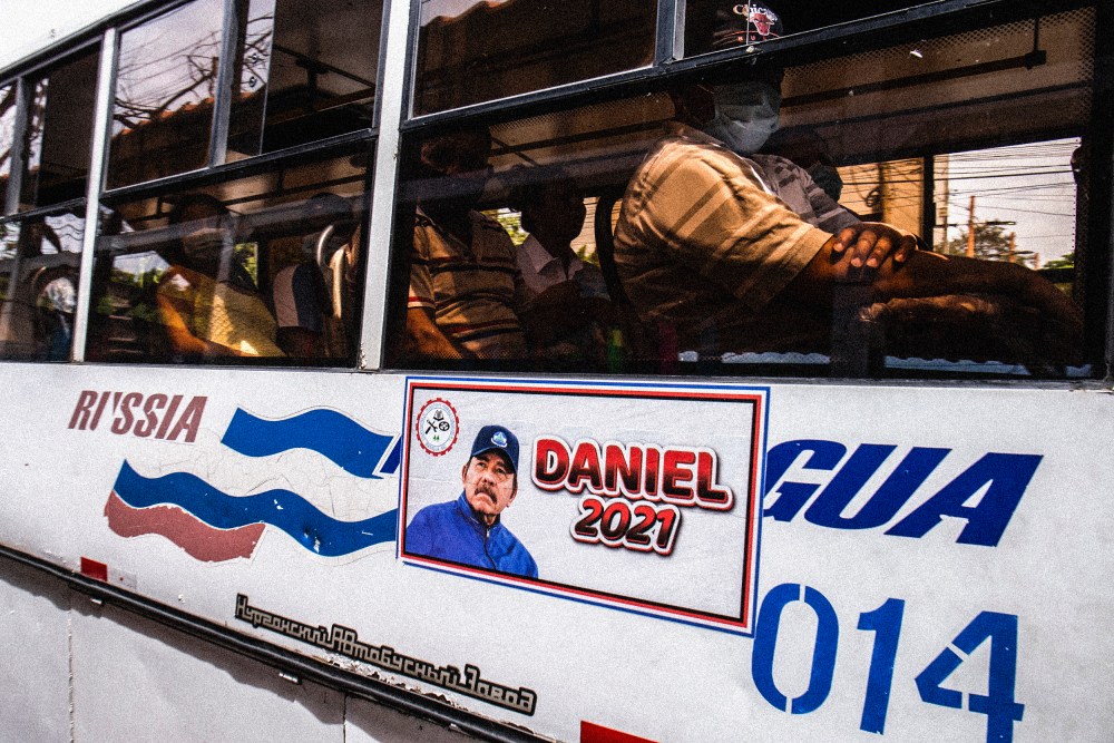 A man rides a bus with a Daniel Ortega campaign sticker on the side in Managua, Nicaragua on June 22, 2021.