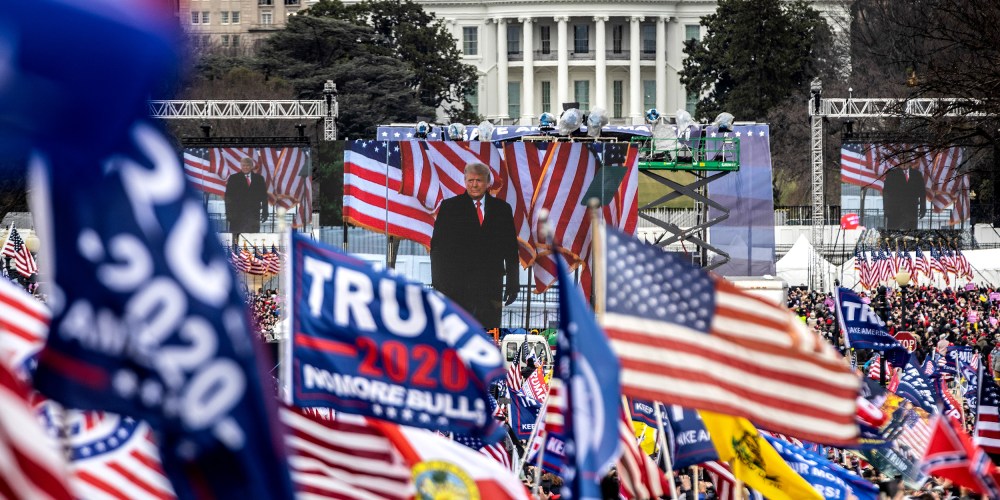 Image: Audience at the crowd waving flags while  Donald Trump is on stage.