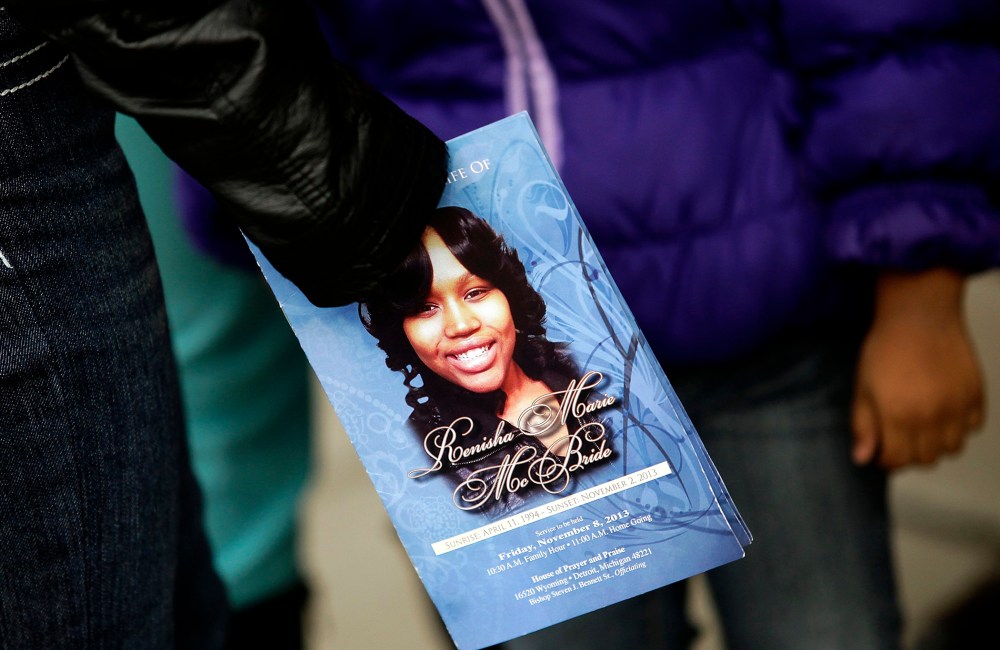 A mourner holds an obituary displaying a picture of shooting victim Renisha McBride during her funeral service in Detroit
