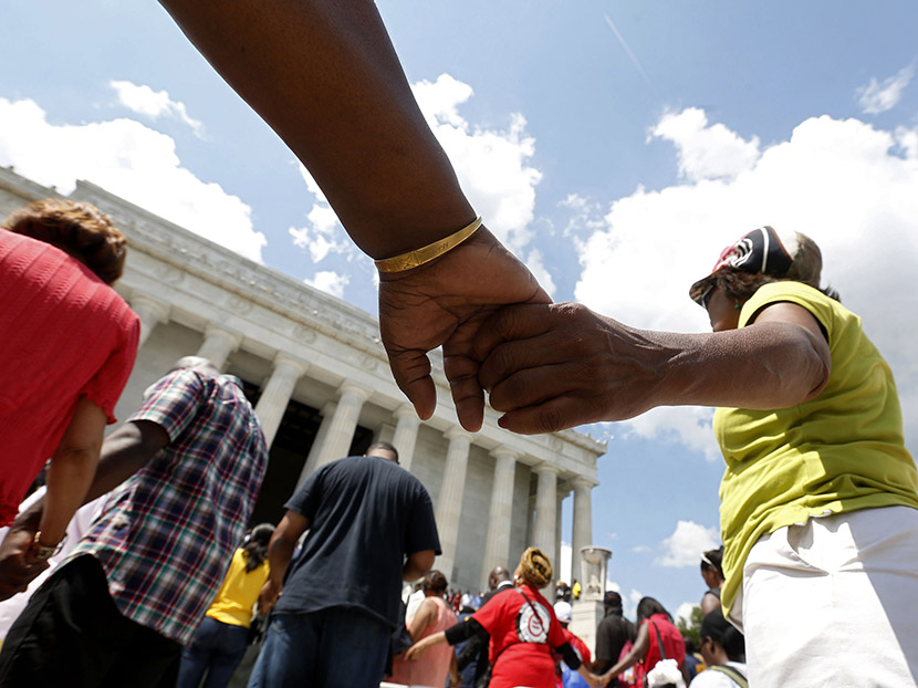 Marchers hold hands in prayer at the 50th anniversary ceremony of the 1963 March ceremony at the Lincoln Memorial on Washington