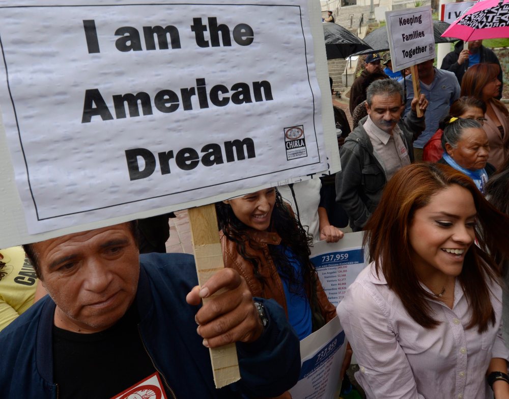 A man holds a poster that reads "I am the American Dream" as he as he joined other immigrants who gathered in front of L.A. City Hall on Nov. 8, 2012. (Photo by Michael Nelson/EPA)
