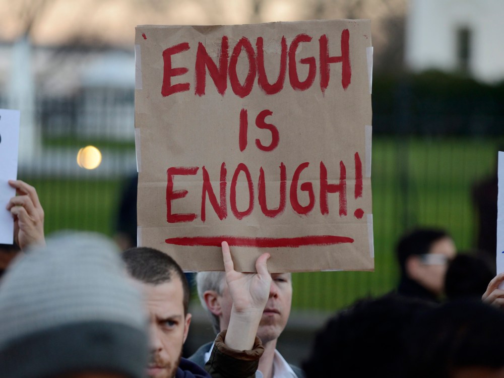 A gun control supporter holds up a sign that reads 'Enough is Enough' during a candlelight vigil for victims of the Sandy Hook Elementary School shooting, outside the White House (Photo by Michael Reynolds/EPA)