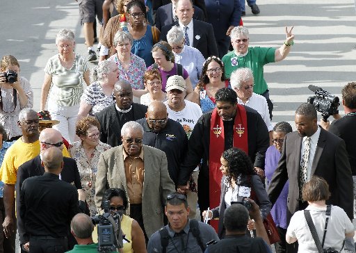 The Rev. William Barber, right center, with red sash, leads a group into the Legislative Building as the Monday protests are held at the General Assembly in Raleigh, NC on Monday, June 3, 2013. (Photo by: Chris Seward/AP Photo/The News & Observer)