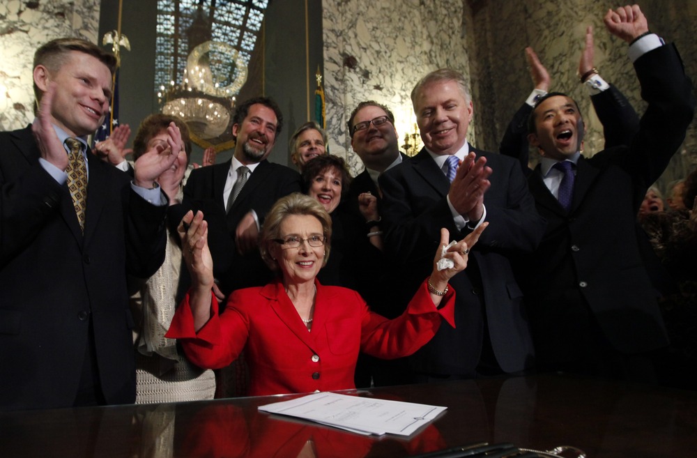 Washington Gov. Christine Gregoire, seated, raises her arms as legislators and supporters cheer behind her after she signed into law a measure that legalizes same-sex marriage Monday, Feb. 13, 2012, in Olympia, Wash.
