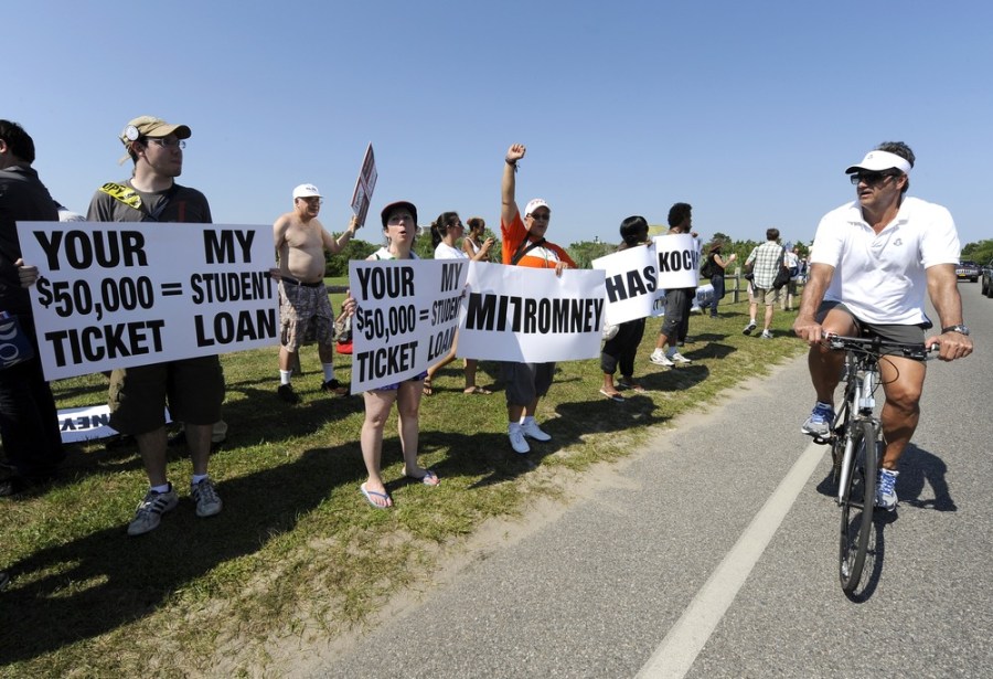 A bicyclist rides past protesters as they demonstrate against a fundraiser for Republican presidential candidate Mitt Romney.