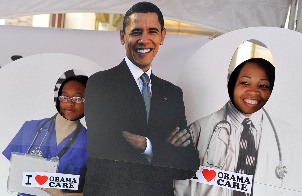 Two girls pose for a picture with a cardboard cut-out of US President Barack Obama in a tent defending "Obamacare" at a street fair in Charlotte, North Carolina, September 3, 2012.