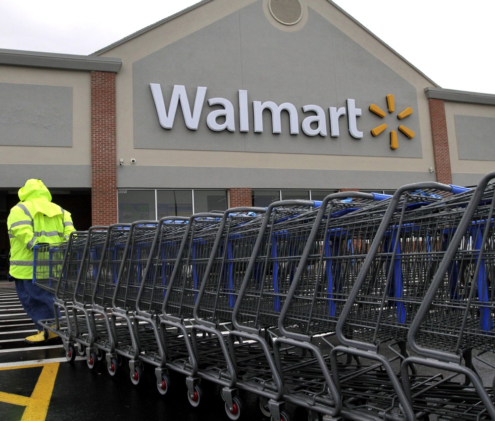 In this Tuesday, Nov. 13, 2012 photo a worker pulls a line of shopping carts toward a Walmart store in North Kingstown, R.I. (AP Photo/Steven Senne)