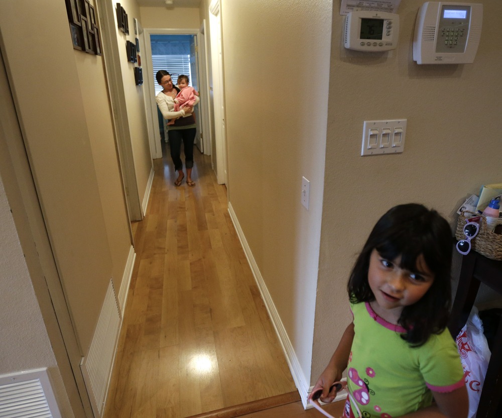 In this Sept. 26, 2012 picture, Domestic worker Alicia Wotherspoon carries Stella Widmann as she begins her day of work at the Widmann home in San Diego. Older daughter Luna Widmann looks on at right. (AP Photo/Gregory Bull)