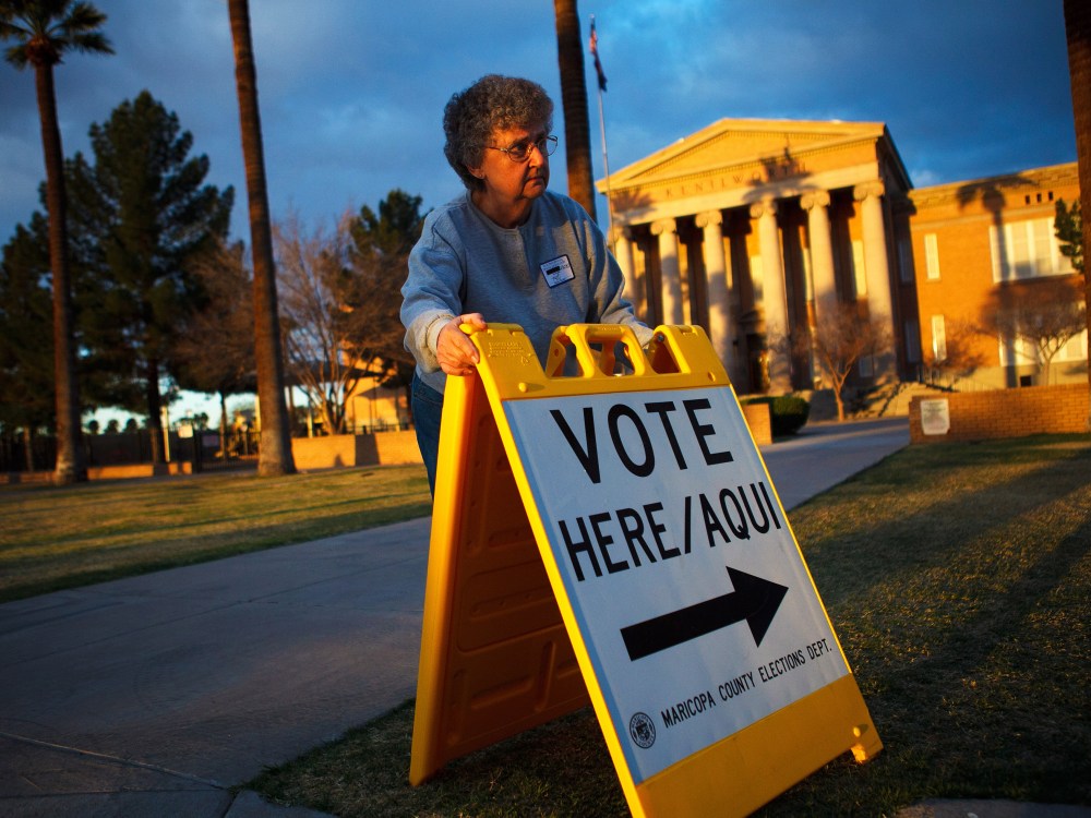 Election day volunteer Vicki Groff places a sign to direct voters to a polling station at Kenilworth School February 28, 2012 in Phoenix, Arizona.
