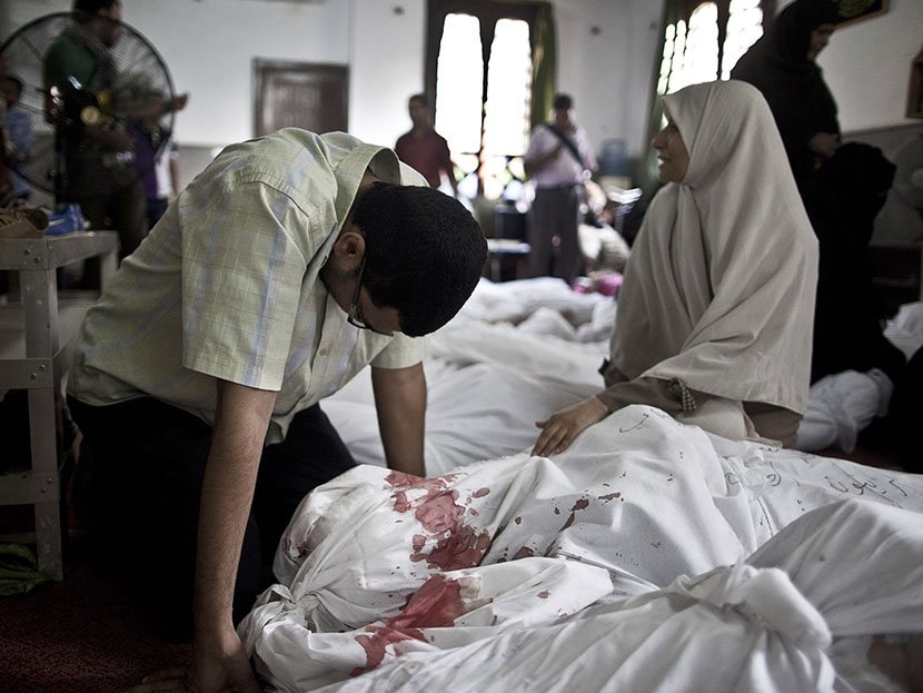 Egyptians mourn over a body wrapped in shrouds at a mosque in Cairo on August 15, 2013, following a crackdown on the protest camps of supporters of ousted Islamist president Mohamed Morsi the previous day. (Photo by Mahmoud Khaled/AFP/Getty Images)