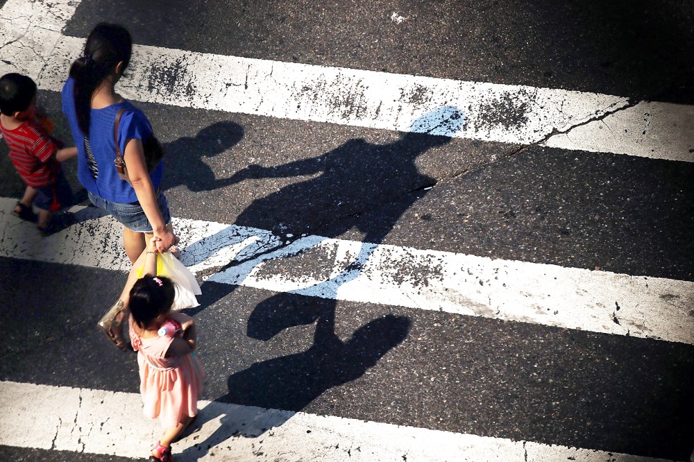 A woman crosses a street with children as seen from the Manhattan Bridge in New York City, on Aug. 21, 2013.