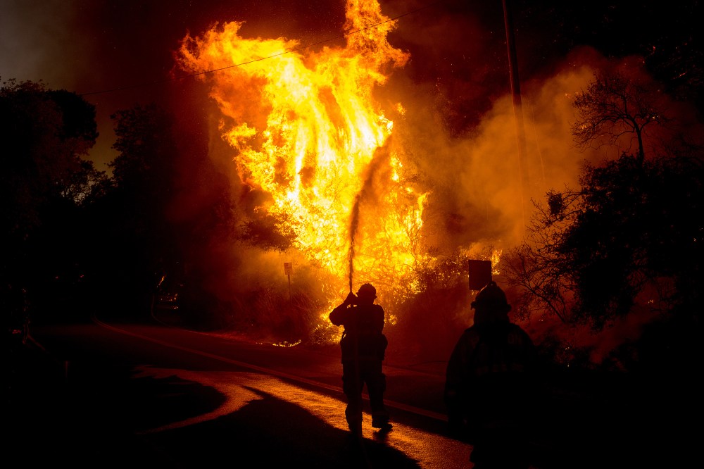 A firefighter sprays water as a wildfire races along Lytle Creek Road near Keenbrook, Calif., Aug. 17, 2016. (Photo by Noah Berger/AP)
