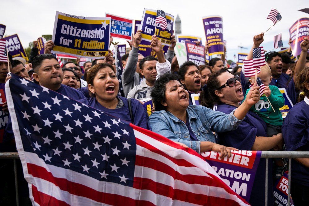 Lorena Ramirez, of Arlington, Va., holds up an American flag as she cheers with her friend Lilia Beiec during a rally in support of immigration reform on Oct. 8, 2013 in Washington, DC. (Drew Angerer/Getty)