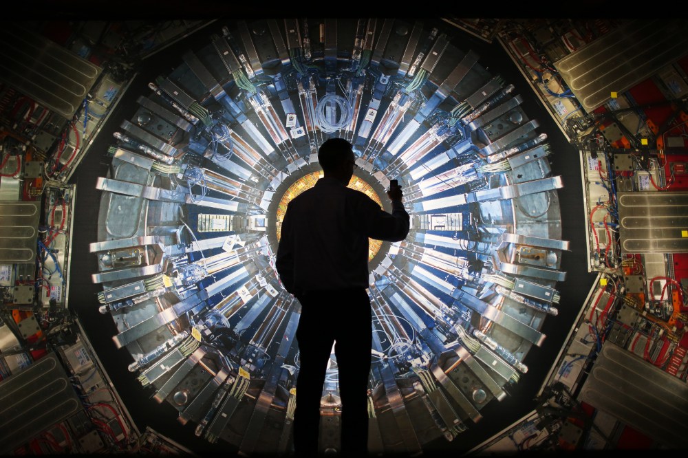 A visitor takes a photograph of an image of the Large Hadron Collider (LHC) at the  Science Museum's 'Collider' exhibition on November 12, 2013 in London, England.