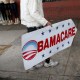 Image: Pedro Rojas holds a sign directing people to an insurance company where they can sign up for the Affordable Care Act, also known as Obamacare