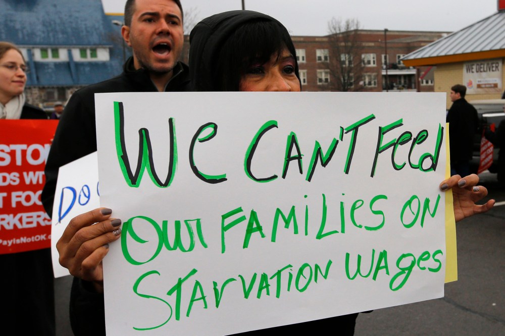 Gladys Jimenez holds a sign during a demonstration in support of higher minimum wages for fast food and other workers outside a Burger King restaurant in Boston, Massachusetts December 5, 2013.