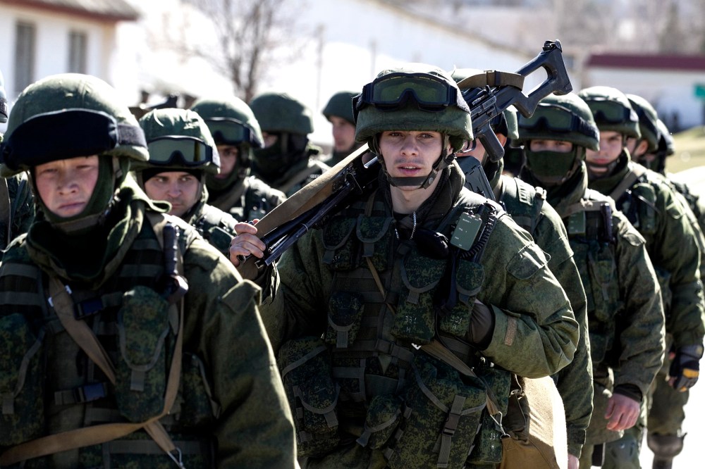 Military personnel, believed to be Russian servicemen, walk outside the territory of a Ukrainian military unit in the village of Perevalnoye outside Simferopol March 3, 2014.