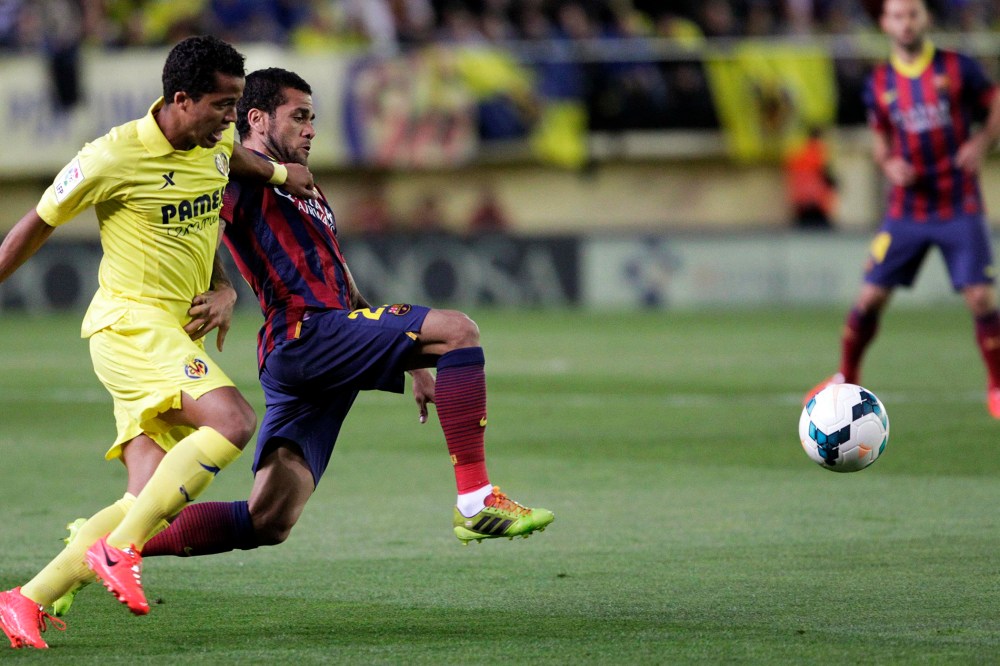 Barcelona's Dani Alves and Villarreal's Giovani Dos Santos fight for the ball during their Spanish first division soccer match at the Madrigal stadium in Villarreal on April 27, 2014.
