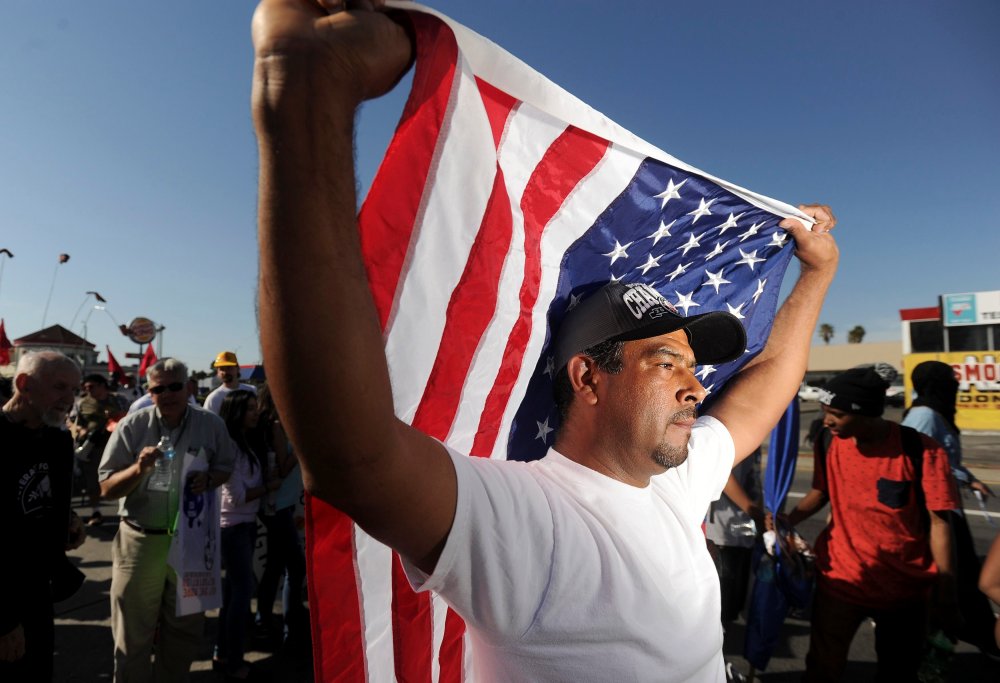 Oscar Rojas carries an American flag during a May Day demonstration in Oakland, California May 1, 2014.