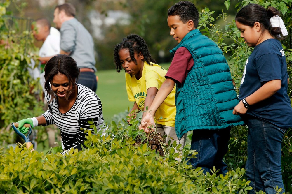 U.S. First Lady Michelle Obama (L) harvests peanuts and other produce from the White House kitchen garden with schoolchildren in Washington on Oct. 14, 2014.