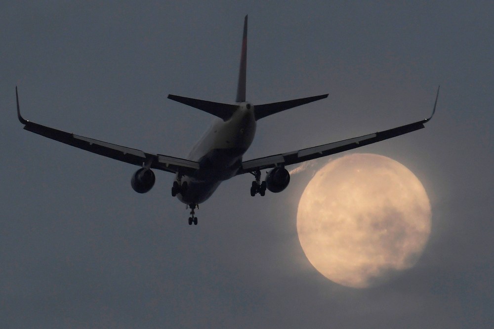 A passenger aircraft makes its landing approach to Heathrow airport in front of a "super moon" at dawn in west London, Britain on Oct. 17, 2016. (Photo by Toby Melville/Reuters)
