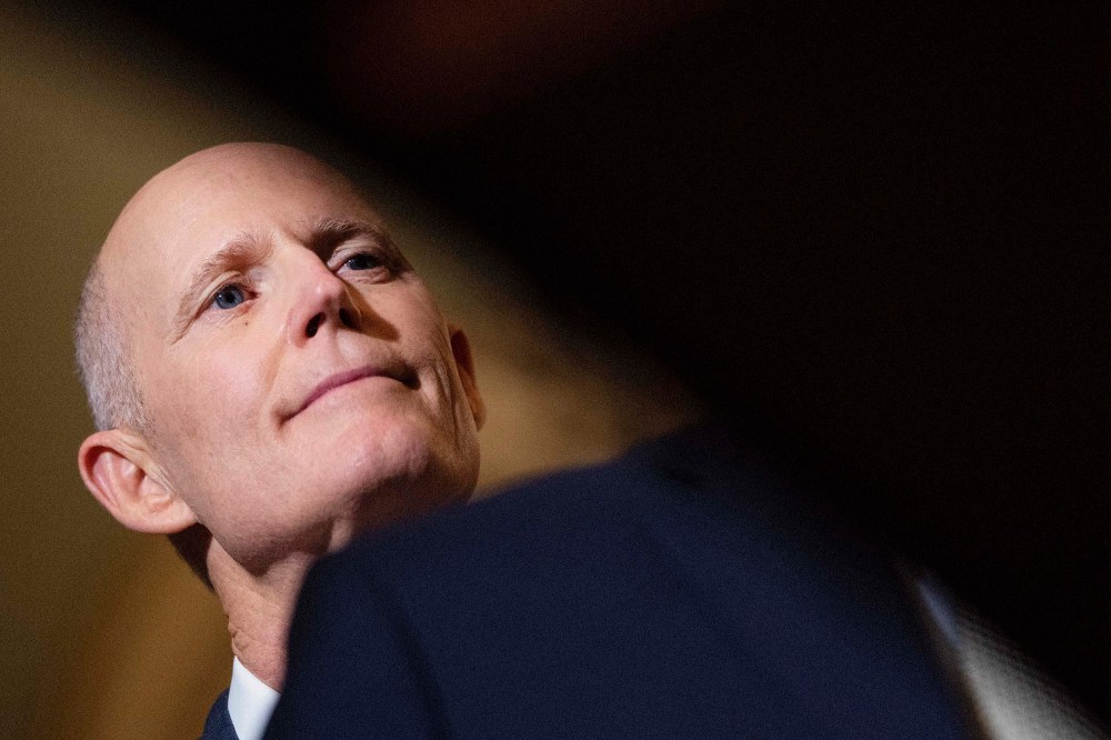 Sen. Rick Scott listens as Senate Minority Leader Mitch McConnell speaks to reporters at the U.S. Capitol March 22 in Washington, D.C.