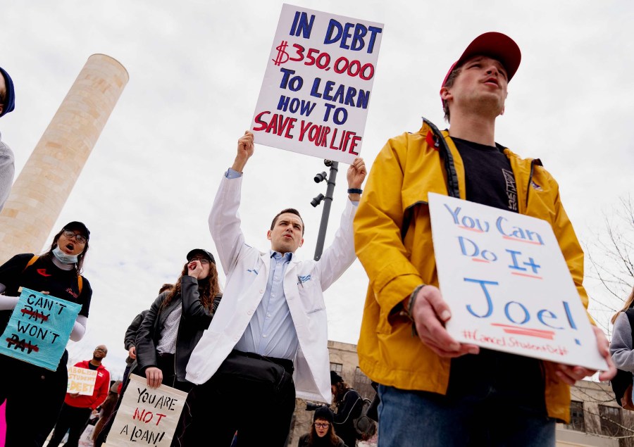 A person wearing a medical jacket holds a sign during a Cancel Student Debt rally outside the US Department of Education in Washington, D.C. on Monday, April 4.