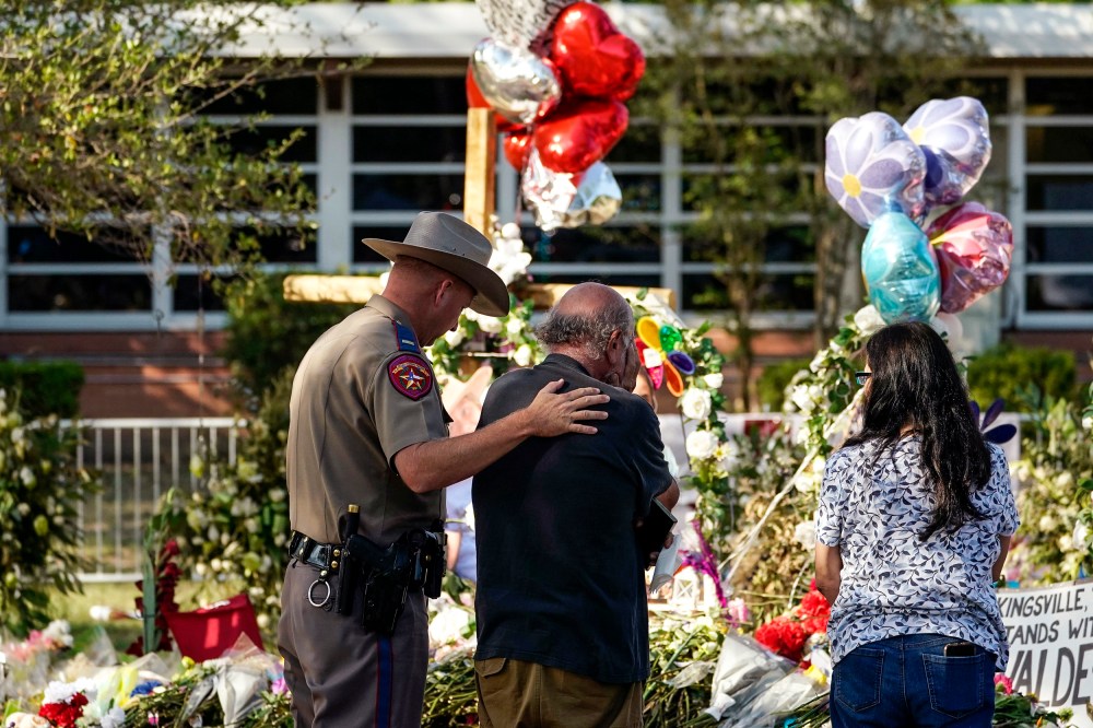 Image: A man is comforted by a Texas Department of Public Safety officer at a memorial outside Robb Elementary School created to honor the victims killed in last week's school shooting, on June 3, 2022, in Uvalde, Texas.