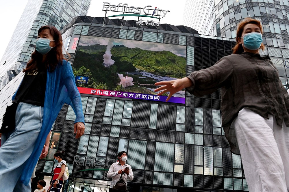 People in front of a large screen showing a news broadcast about China's military exercises encircling Taiwan in Beijing on Thursday.