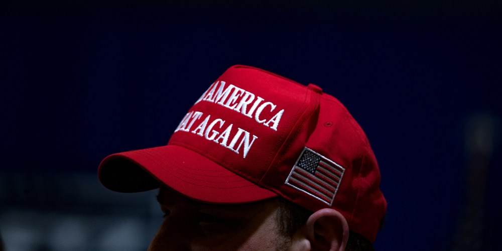 Image: A supporter at a rally wearing a red hat that reads,"Make America Great Again".