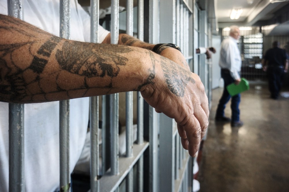 ANGOLA PRISON, LOUISIANA - OCTOBER 14, 2013:
A prisoner's hands inside a punishment cell wing at Angola prison.
The Louisiana State Penitentiary, also known as Angola, and nicknamed the "Alcatraz of the South" and "The Farm" is a maximum-security prison farm in Louisiana operated by the Louisiana Department of Public Safety & Corrections. It is named Angola after the former plantation that occupied this territory, which was named for the African country that was the origin of many enslaved Africans brought to Louisiana in slavery times.
This is the largest maximum-security prison in the United States[with 6,300 prisoners and 1,800 staff, including corrections officers, janitors, maintenance, and wardens. It is located on an 18,000-acre (7,300 ha) property that was previously known as the Angola Plantations and bordered on three sides by the Mississippi River.
