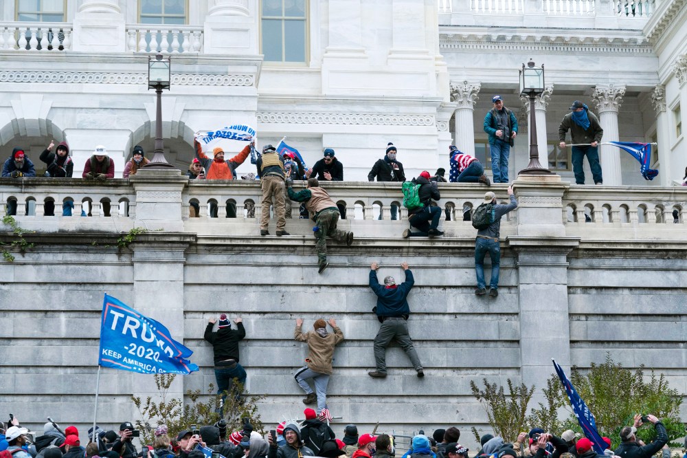 Rioters climb the west wall of the the Capitol