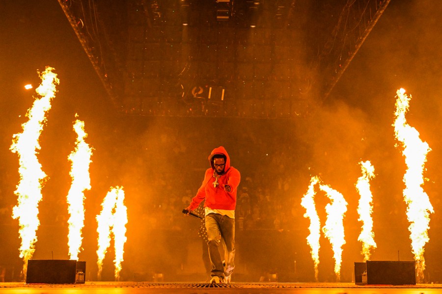 Kendrick Lamar walks on stage between two rows of flames shooting upwards