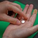 A hand holds a Mifepristone pill.