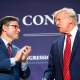 Mike Johnson, left, and Donald Trump speak to each other on stage