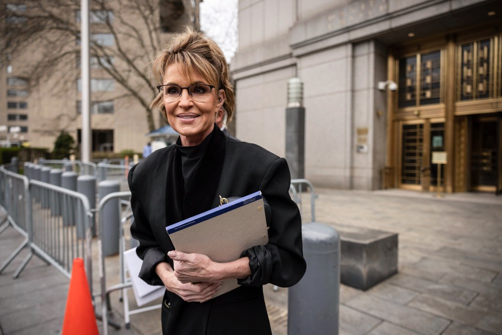 Sarah Palin walks outside holding a notepad