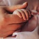 A close-up of a mother gently holding her baby's tiny hand,.