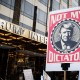 A marcher holds a sign that says, "Not My Dictator" with a picture of Donald Trump in front of Trump International Tower