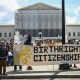 Image: People hold banners and signs as they participate in a protest outside the Supreme Court