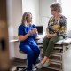 Female doctor in scrubs consulting with senior woman in exam room