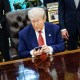 Donald Trump uses his cellphone at his desk in the Oval Office