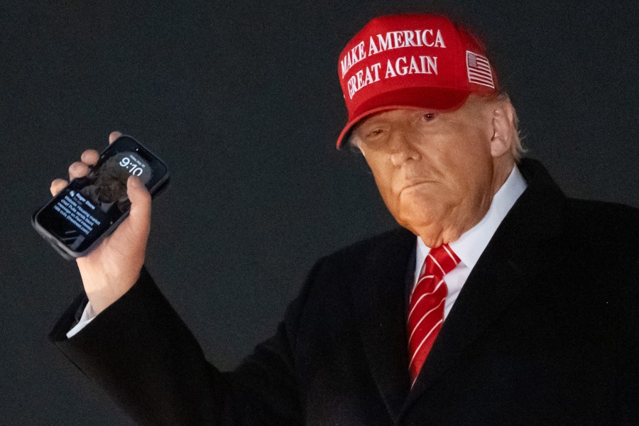 President Donald Trump disembarks from Air Force One while holding his cellphone with a text message from Roger Stone