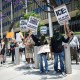 Protestors hold anti-ICE signs on the sidewalk outside of a building