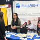A woman speaks to another woman across a table at a Fulbright Program information booth